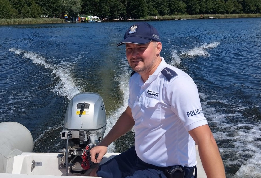 Policjant płynie łądzią po jeziorze.