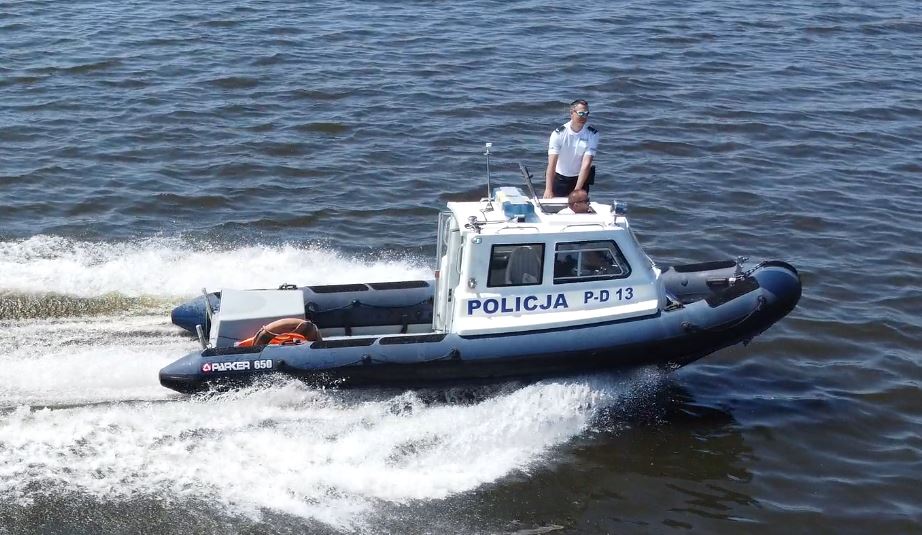 Policjanci na łodzi policyjnej patroluja jezioro.