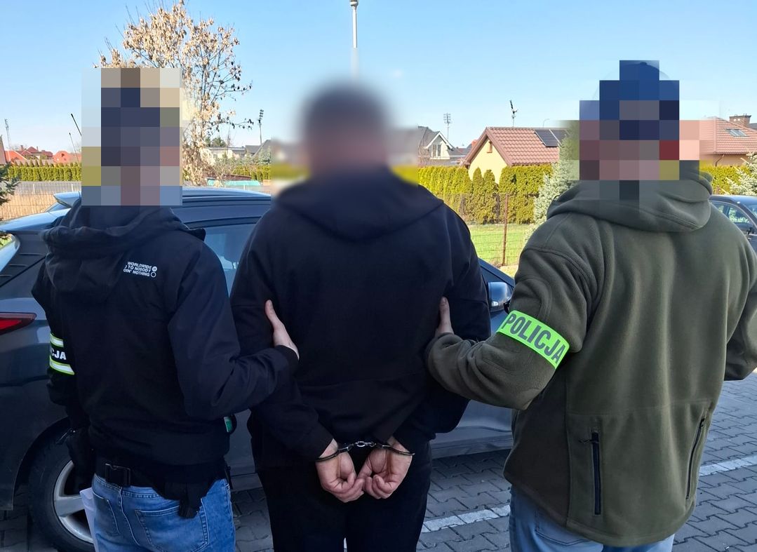 Policjanci prowadzą zatrzymanego mężczyznę.