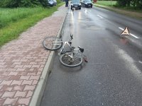 rower leżący częściowo na drodze częściowo na chodniku