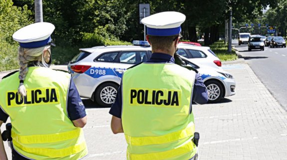 policjanci stojący od tyłu na tle drogi