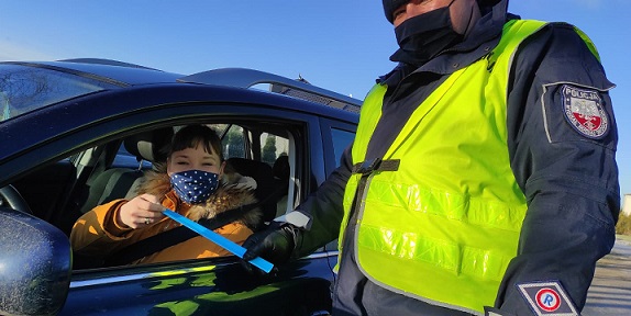 policjant wręcza odblask kobiecie, kierującej pojazdem