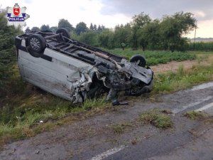 rozbity samochód koloru białego leżący na dachu na poboczu