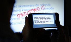 W pierwszym planie zdjęcia widzimy telefon komórkowy trzymany w rękach z wyświetlającym się napisem stworzonym przez oszustów o obowiązku odbycia 10 dniowej kwarantanny