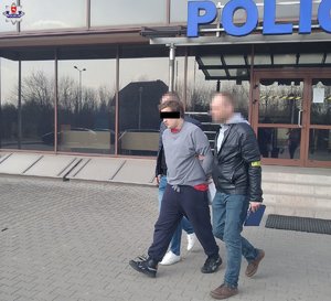 mężczyzna prowadzony przez dwóch policjantów