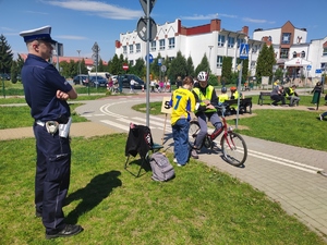policjant obserwujący przejazd ucznia po miasteczku ruchu drogowego