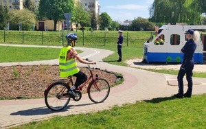 rowerzysta pokonuje trasę po miasteczku ruchu drogowego pod nadzorem policjant