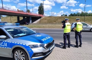 policjanci podczas kontroli uczestników ruchu w tle radiowóz