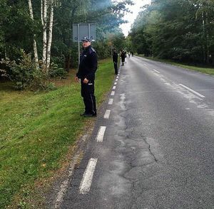 policjanci i strażacy stojący wzdłuż drogi