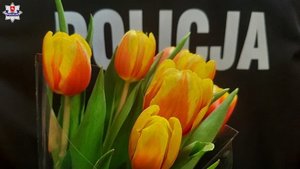 tulipany koloru zółto pomarańczowego na tle napisu Policja