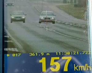 wynik 157 kilometrów na godzinę widoczny na wyświetlaczu urządzenia pomiarowego i w tle pojaz