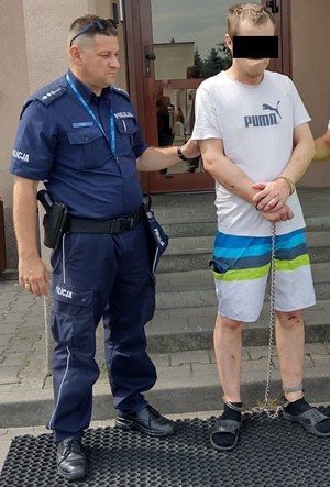 policjant podczas doprowadzenia zatrzymanego