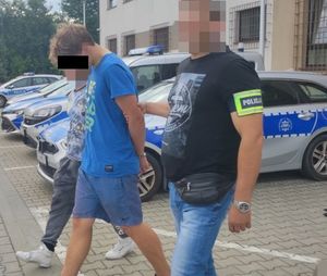 Policjanci doprowadzają zatrzymanego 17-latka w tle radiowozy