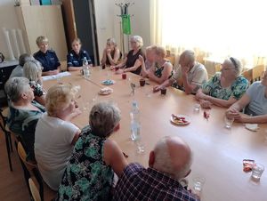 seniorzy i policjantki siedzące pry stole