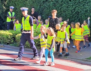 policjant przeprowadzający dzieci przez przejście dla pieszych