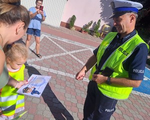 policjant z dzieckiem które wręcza laurkę z podziękowaniem