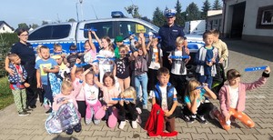 zdjęcie grupowe policjanci z dziećmi które trzymają elementy odbalskowe