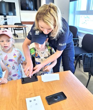 policjantka z dziećmi podczas wykonywania odcisków palców