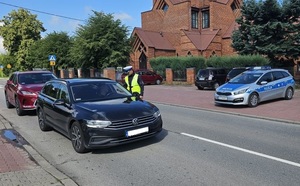 policjant sprawdzający trzeźwość kierującego czarnym autem