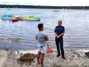 policjantka nad jeziorem podczas rozmowy z plażowiczem