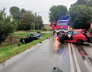 dwa pojazdy po wypadku w tle straż pożarna