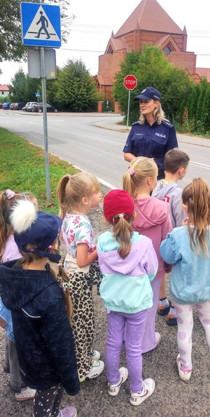 policjantka z dziećmi omawia znaki drogowe