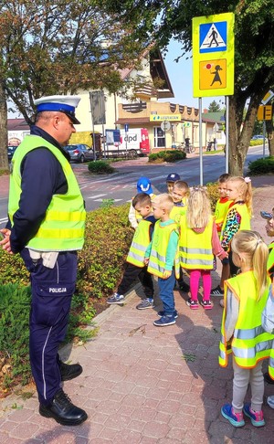 policjant z dziećmi przed przejściem dla pieszych