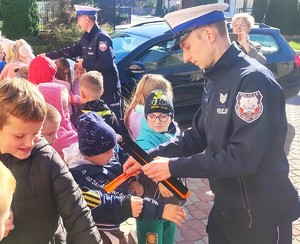 policjant wręcza odblaski dzieciom