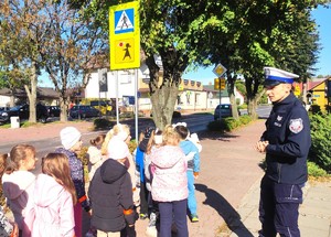 policjant przed przejściem dla pieszych z dziećmi