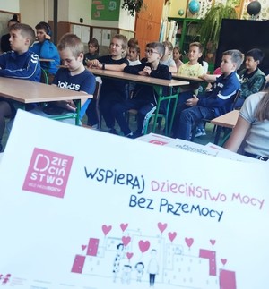 dzieci siedzące przy stolikach w sali lekcyjnej