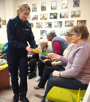 policjantka przekazuje seniorom elementy odblaskowe