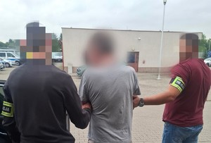 policjanci doprowadzają zatrzymanego