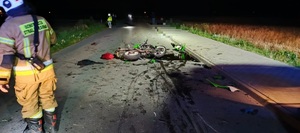 uszkodzony motocykl po wypadku na drodze w tle strażak i policjant