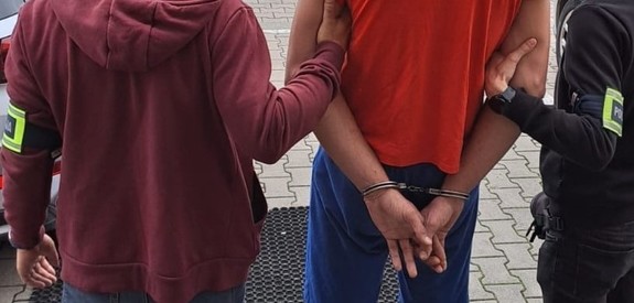 policjanci podczas doprowadzenia zatrzymanego mężczyzny