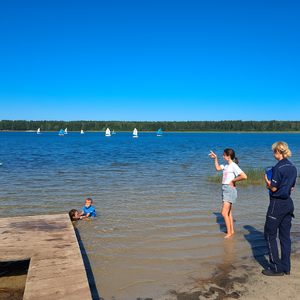 policjantka rozmawiająca z plażowiczką nad jeziorem