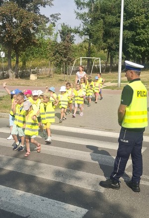 policjant z dziećmi na przejściu dla pieszych