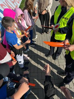 policjantki z dziećmi rozdające opaski odblaskowe