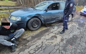41-latek siedzący przy samochodzie. Obok policjant