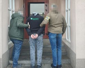 policjanci prowadzą zatrzymanego do budynku