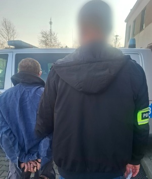 zatrzymany mężczyzna podczas doprowadzenia przez policjantów