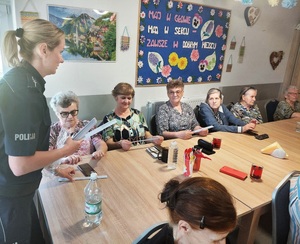 policjantka przekazuje seniorom elementy odblaskowe