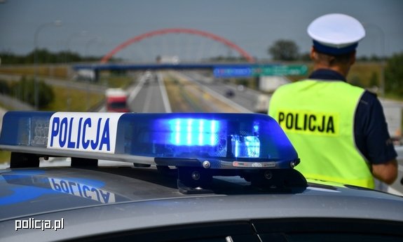Policjant ruchu drogowego stoi przy radiowozie.