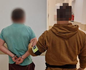 policjant doprowadza zatrzymanego mężczyznę