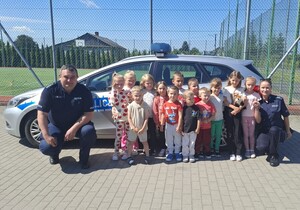 policjanci z dziećmi przy radiowozie