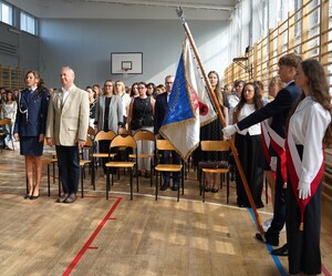sztandar szkoły, w tle policjantka i uczniowie