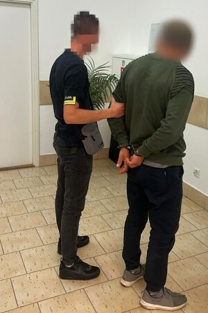 policjant podczas doprowadzenia zatrzymanego mężczyzny