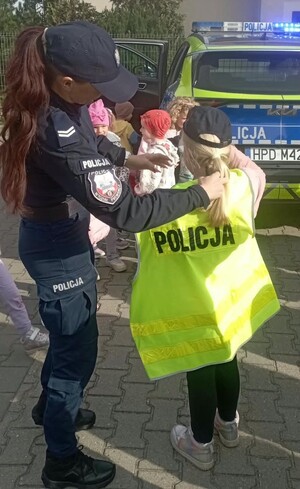 policjantka nakłada dziecku kamizelkę odblaskową