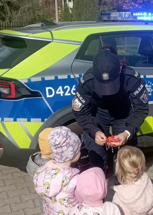 policjantka przekazuje elementy odblaskowe dzieciom